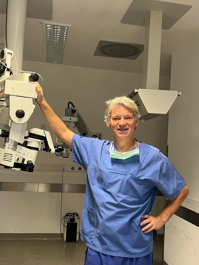 Dr. Georg Gerten im OP-Kittel neben dem Zeiss Operationsmikroskop